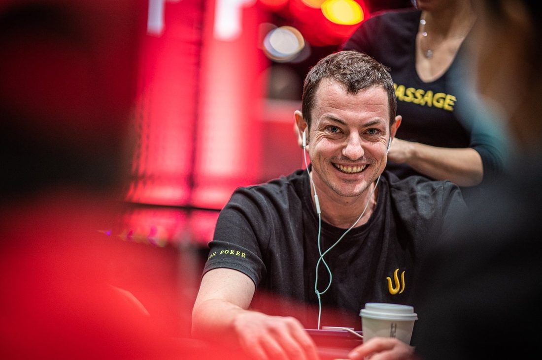 Poker pro smiling at the table under red light, photographed by Drew Amato